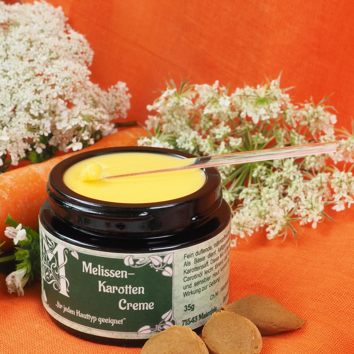 Geöffneter 35ml Melissen-Karotten Creme Tiegel, Auf der Creme liegt ein Glasspatel, der Creme entnimmt.