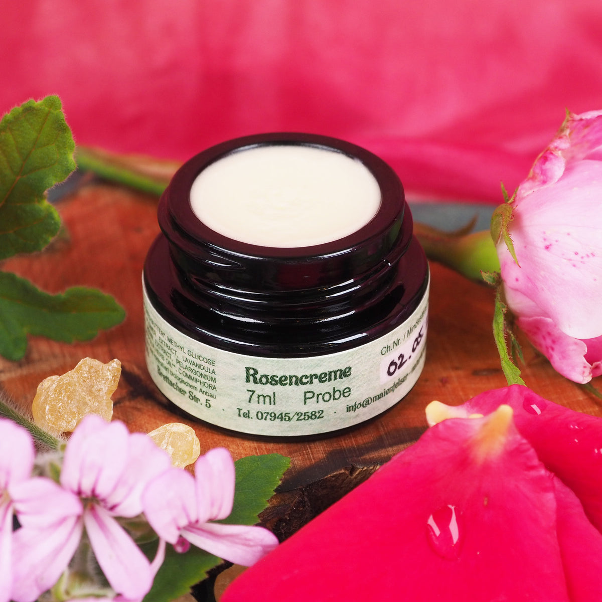 Geöffneter 7ml Rosencreme Tiegel. Daneben liegt eine Rose.
