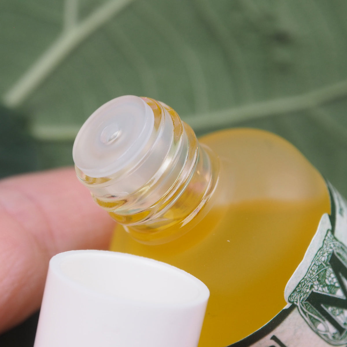 geöffnete Glaschlasche mit durchsichtigem Tropfeinsatz. Es wird angedeutet das etwas aus der Flasche in den Deckel geschüttet werden soll.